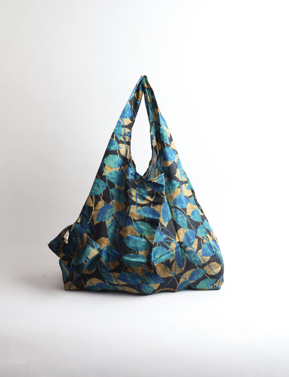 Blue reusable bag with tropical floral pattern in pink, yellow, and green, shown hanging with handles visible