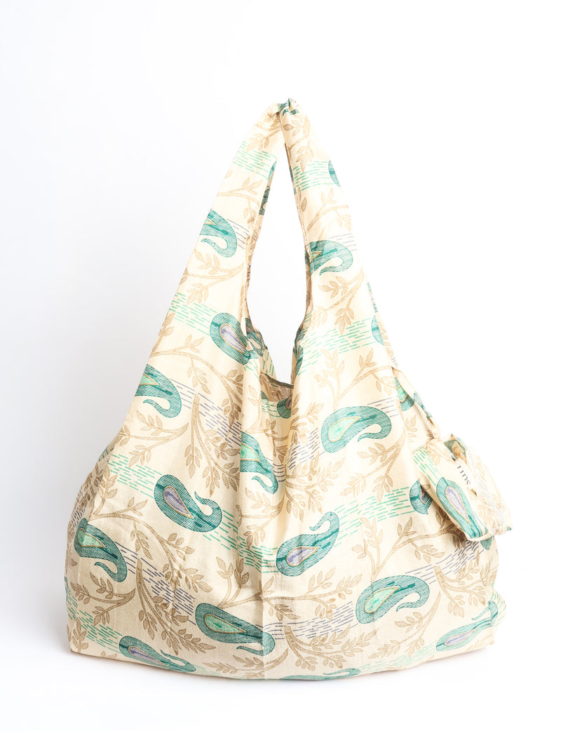Blue reusable bag with multicolor tropical floral pattern folded with "I was a sari" label visible on front
