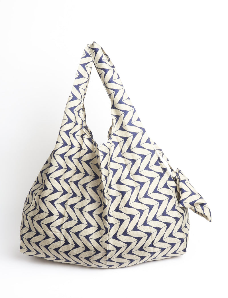 Blue reusable bag with multicolor tropical floral pattern folded with "I was a sari" label visible on front