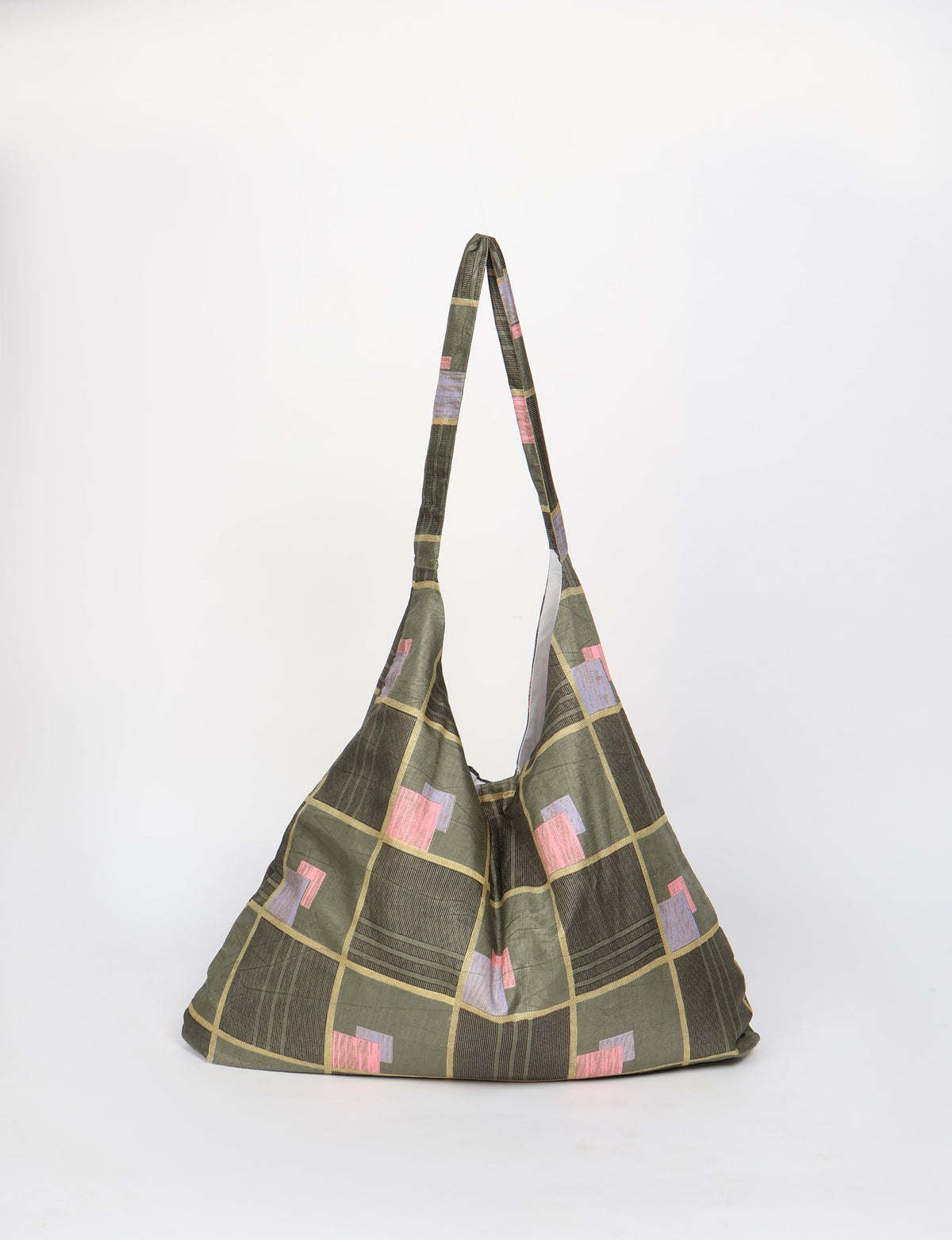 Green trapeze bag with geometric square pattern in pink, purple, and beige, shown hanging against white background