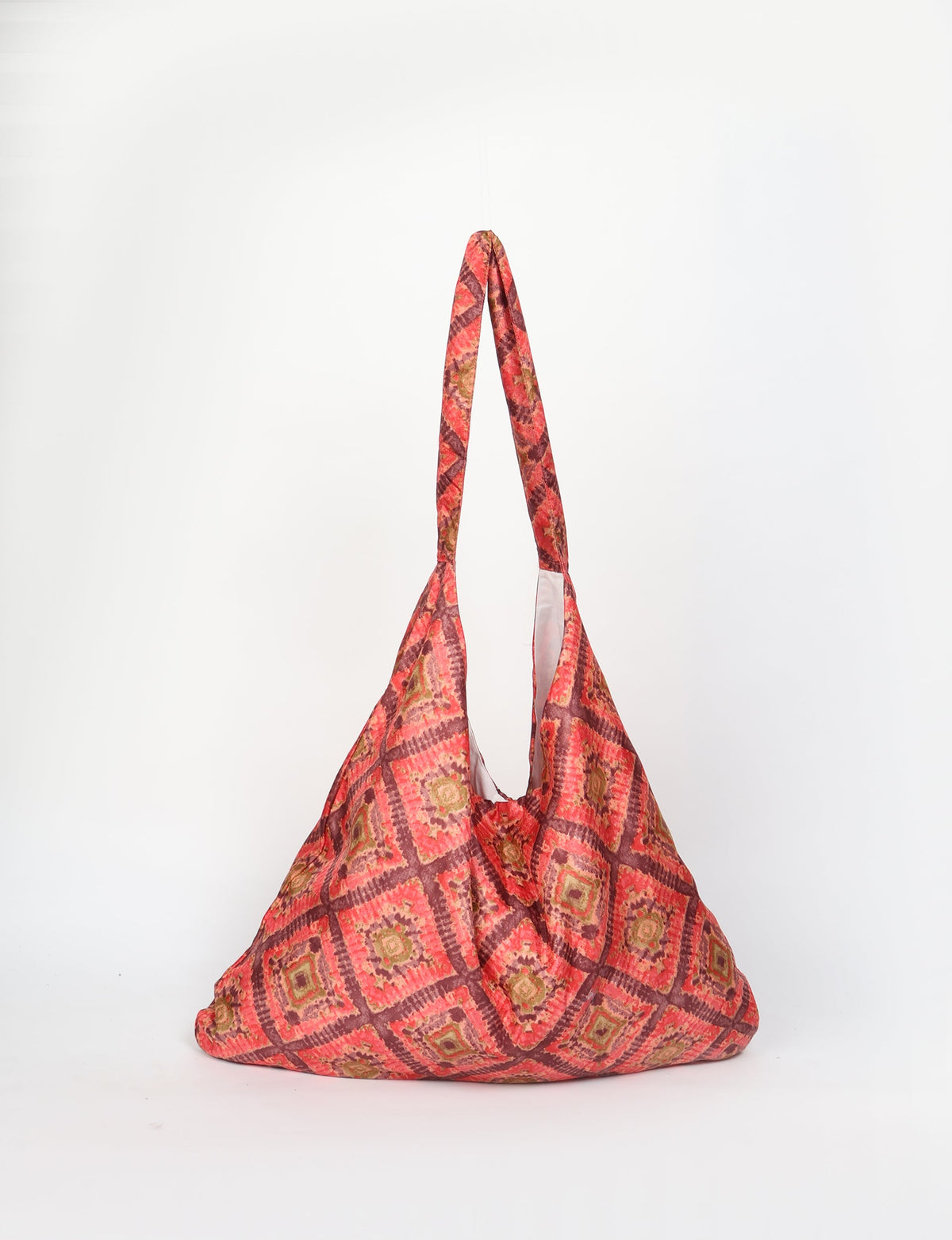Orange trapeze bag with Indian ethnic geometric pattern in red, brown, and green, shown hanging front view