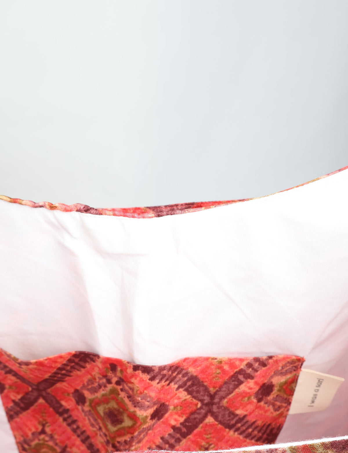 Orange trapeze bag with Indian ethnic pattern, showing white interior lining and inner pocket with label
