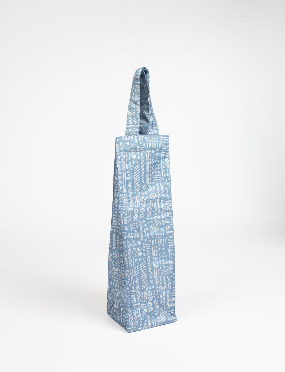 Blue fabric wine bag with white Indian ethnic geometric patterns, hanging by its handle against a white background