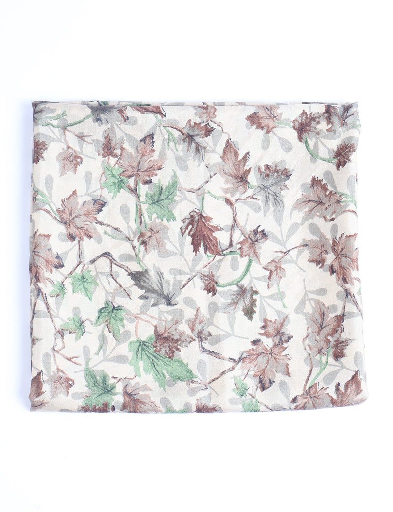 Beige pareo folded flat with a leaf pattern in brown, green, and gray tones on a light background