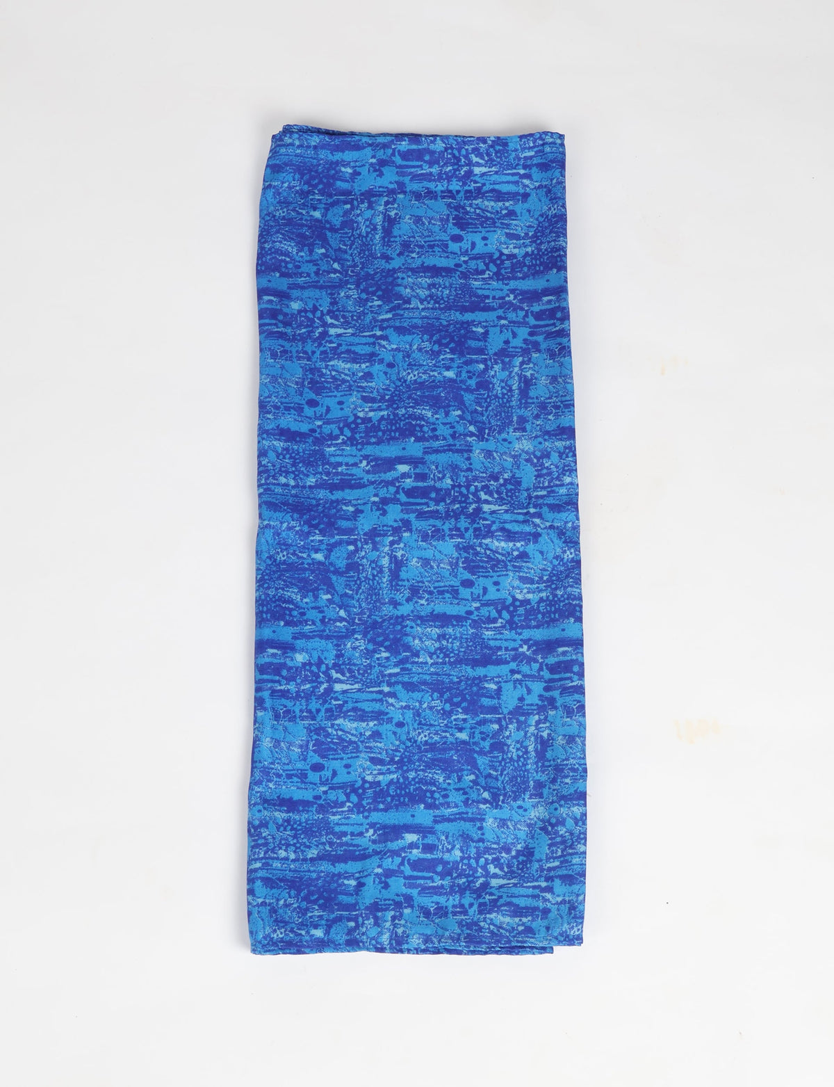 Folded blue stole with an abstract pattern in various shades of blue, flat lay on a white background