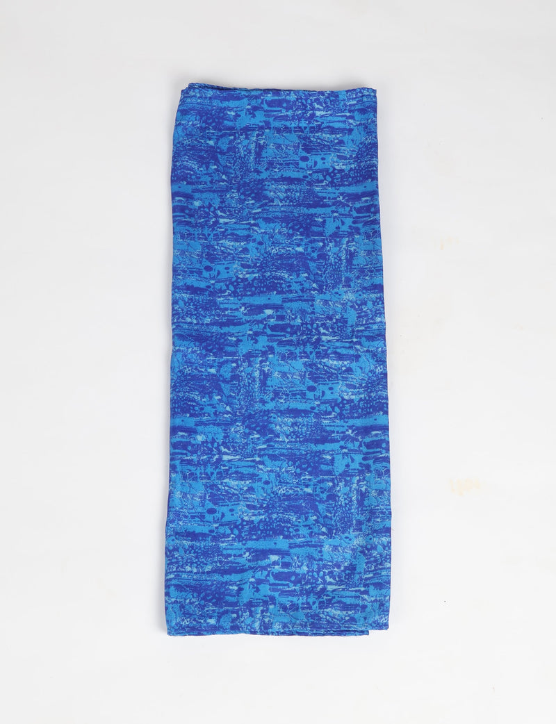 Folded blue stole with an abstract pattern in various shades of blue, flat lay on a white background