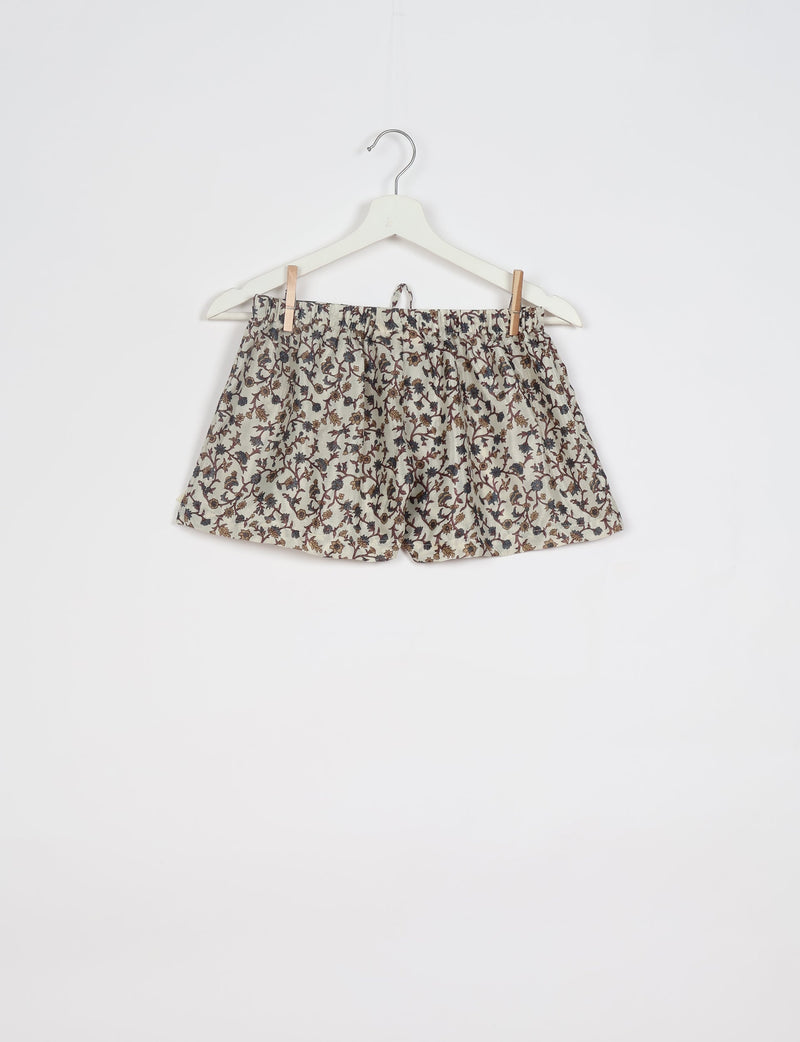 Beige shorts with brown and black floral print, elastic waistband, hanging on white hanger against white background
