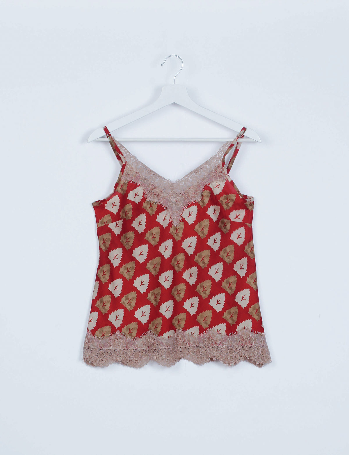 Red floral sleeveless pajama top with beige lace trim on neckline and hem, hanging on white hanger against white background