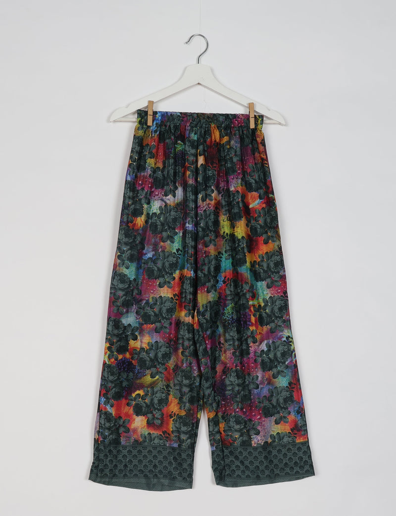 Colorful abstract floral print pajama pants with elastic waistband and dark patterned cuffs hanging on white hanger