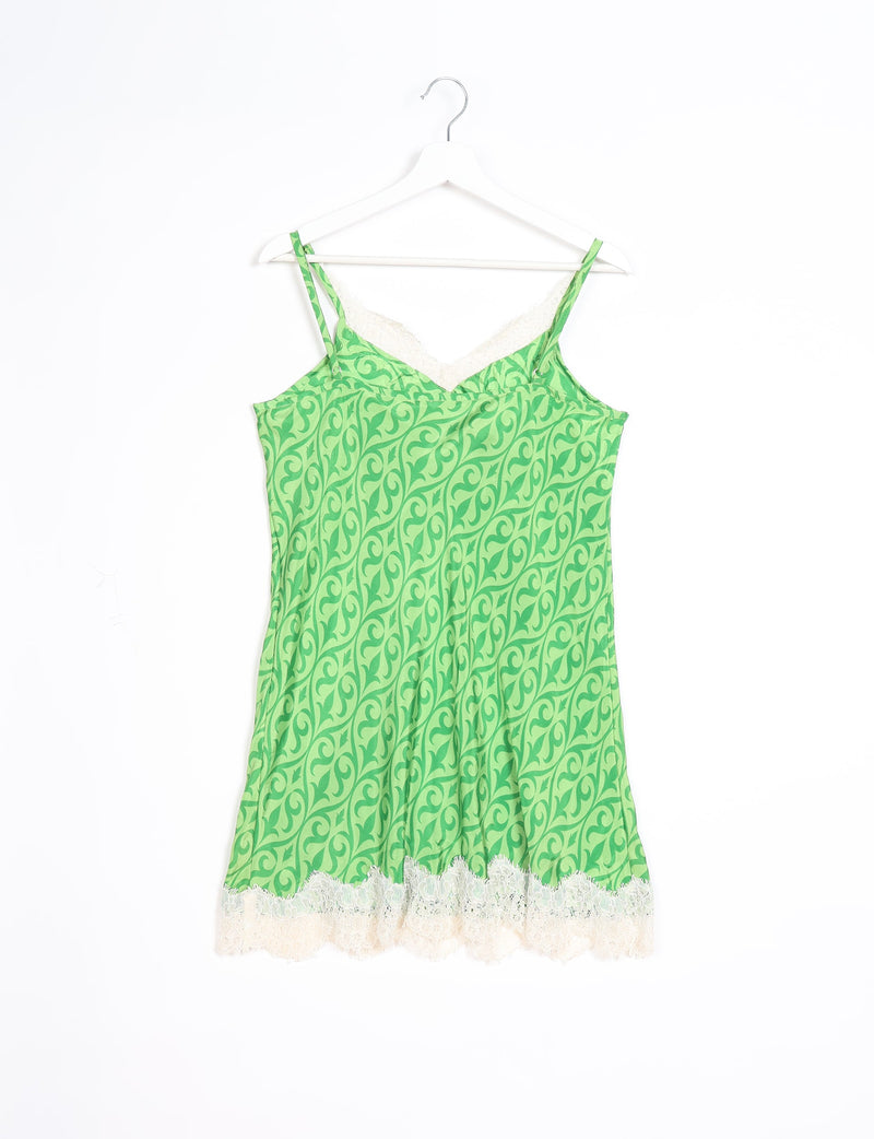 Green ethnic night dress with white lace trim, sleeveless with thin straps, hanging on a white hanger against a white background