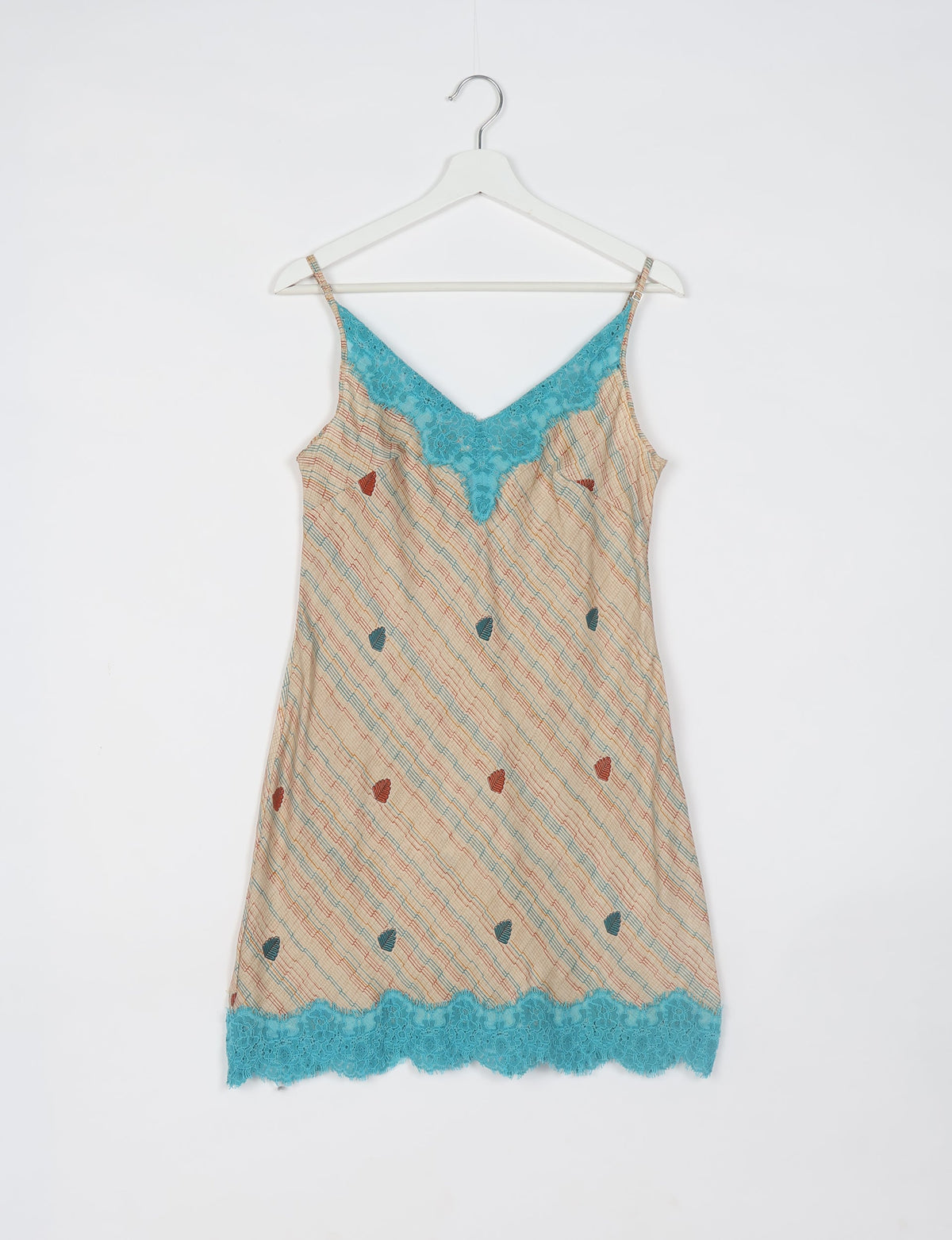 Beige night dress with abstract pattern, blue lace trim at neckline and hem, adjustable spaghetti straps, hanging on white
