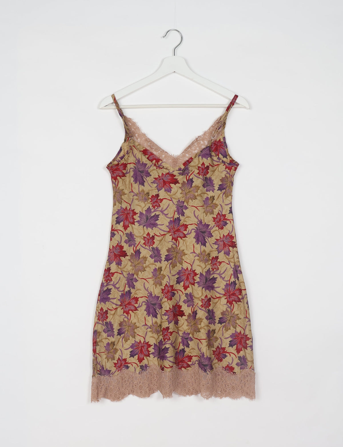 Beige night dress with red and purple leaf print, lace trim at neckline and hem, hanging on white hanger, front view