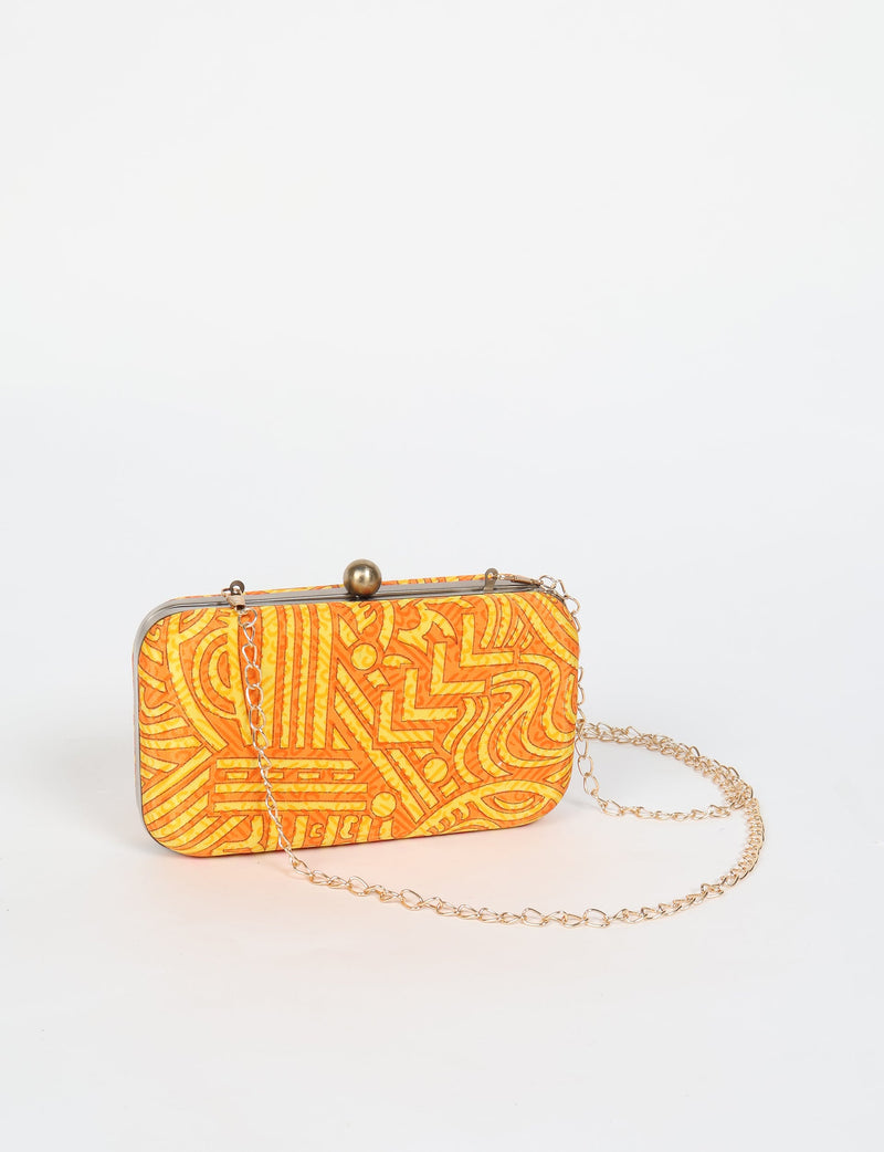 Yellow abstract patterned clutch handbag with metal frame, ball clasp, and gold chain strap, shown front view on white background