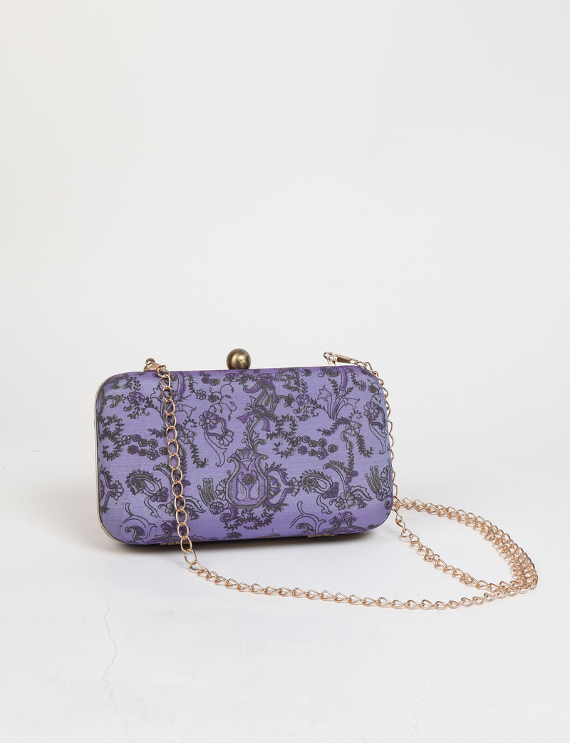 Purple clutch handbag with black tropical floral pattern and gold chain strap, front view on white background