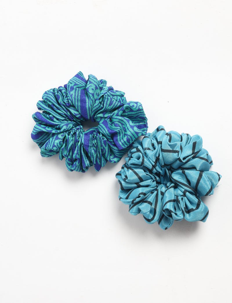Set of two fabric scrunchies, one with blue and green abstract pattern, the other light blue with black abstract lines, flat