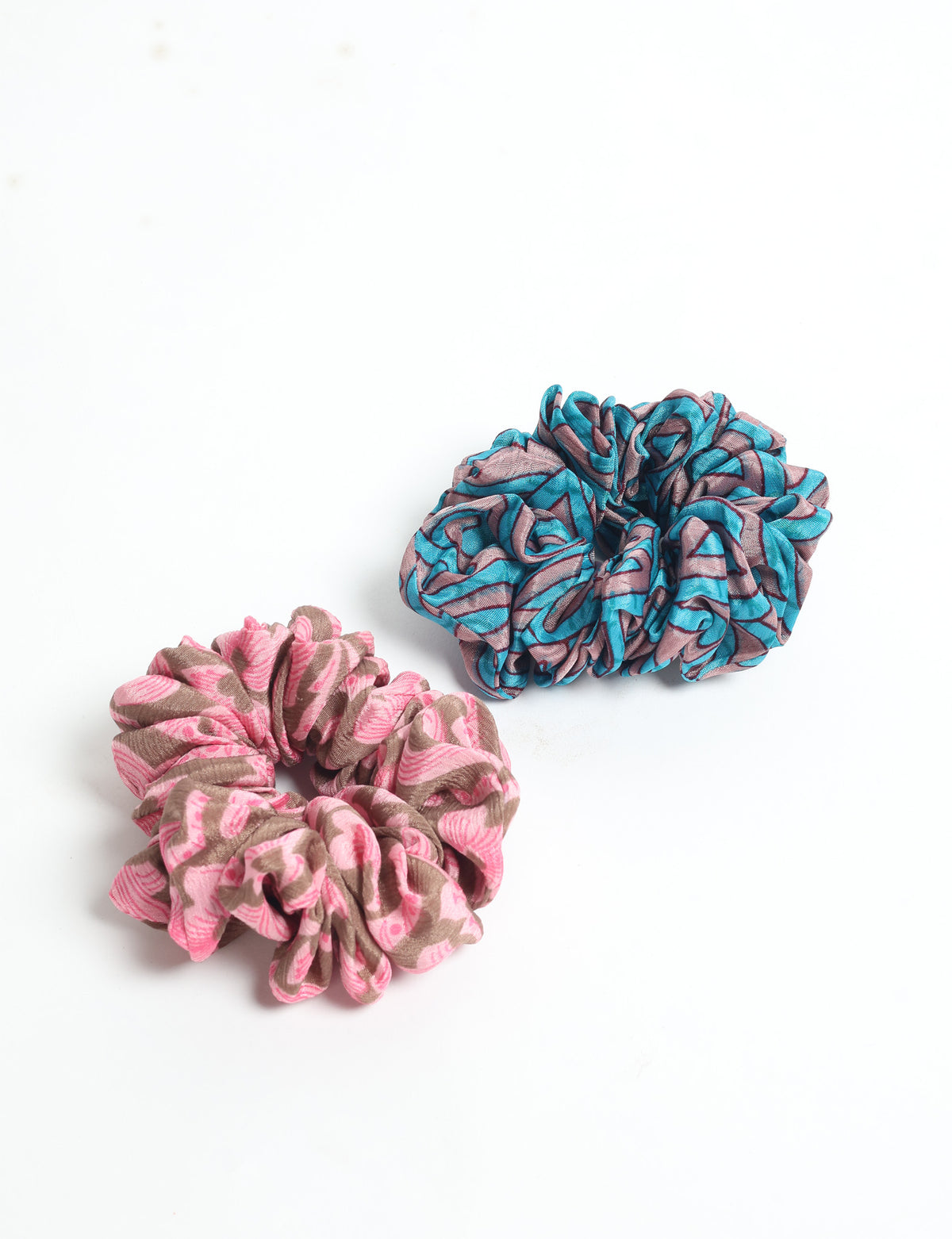 Set of 2 assorted scrunchies with pink and brown, and blue and brown abstract patterns, flat lay on white background