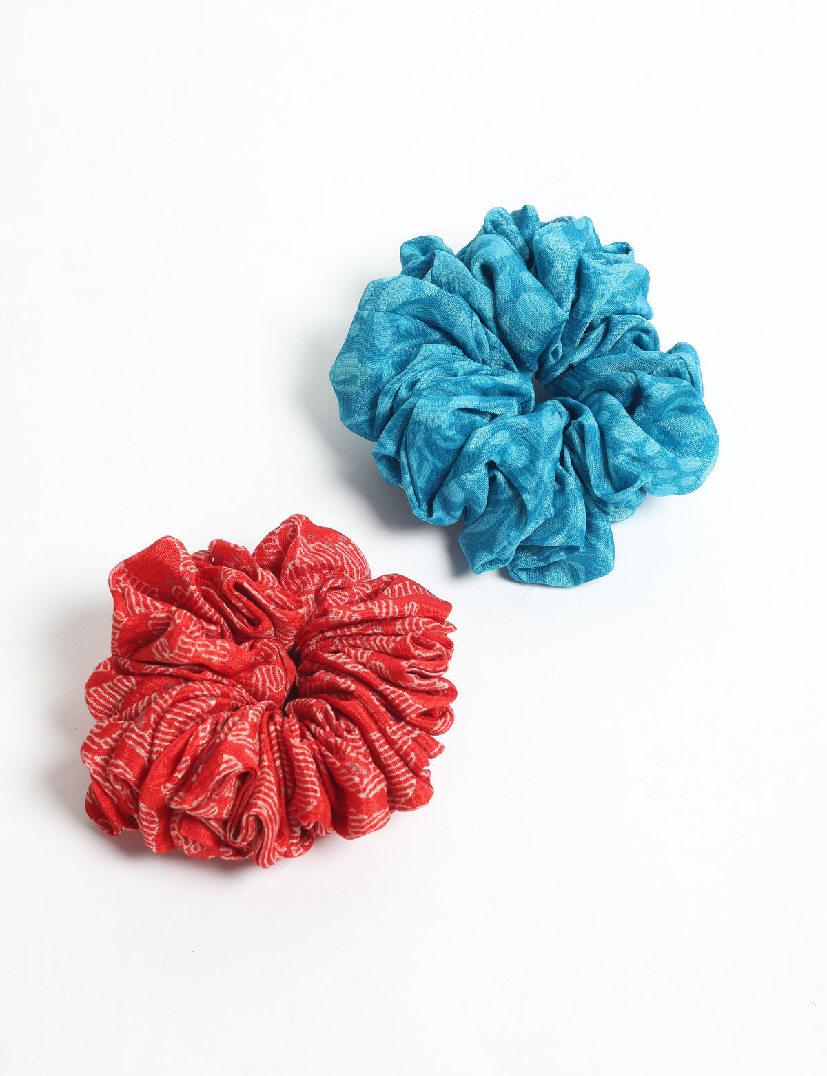 Set of two scrunchies, one red with white text pattern and one solid blue, shown flat on white background