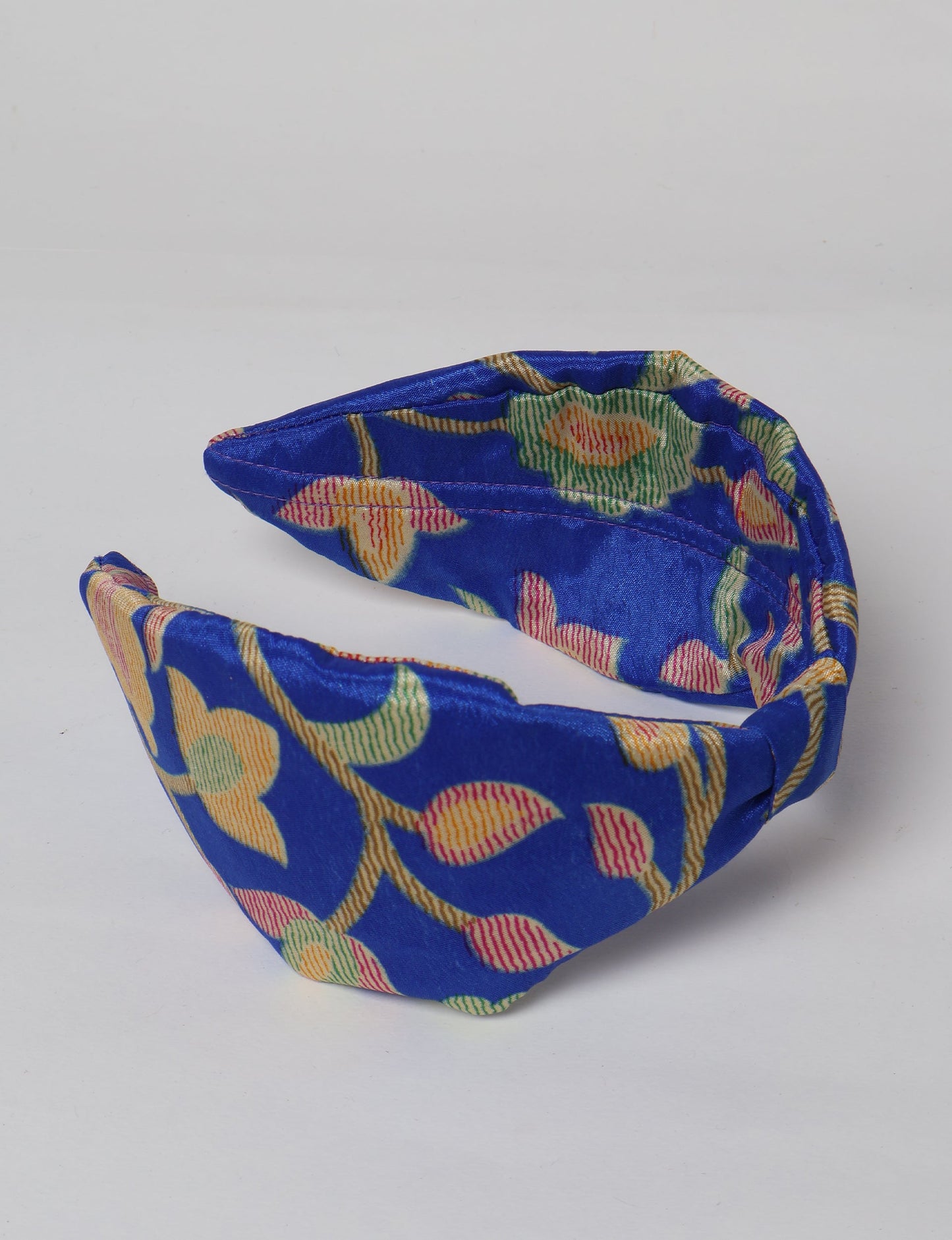 Upcycled sari hairband with central knot, handmade in India — an eco friendly fashion accessory representing green fashion, upcycled women’s clothing, fair trade fashion, and earth friendly clothing made from recycled sari textiles.