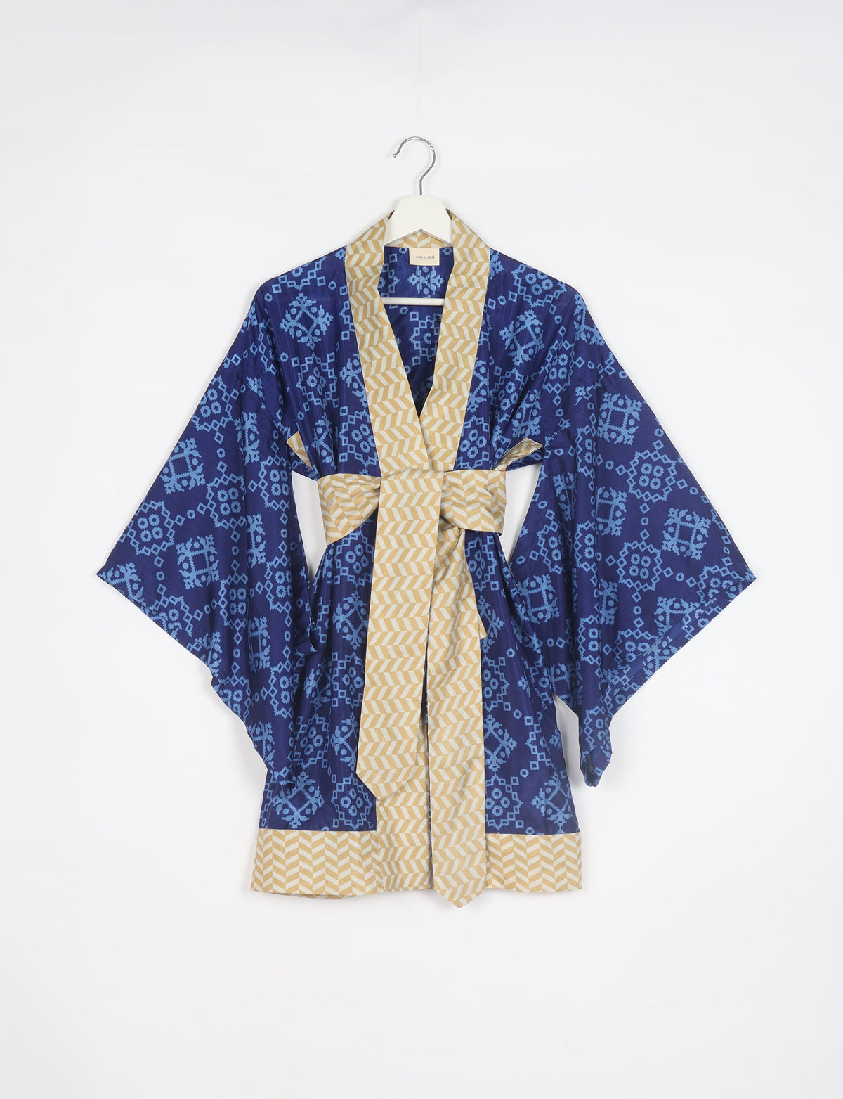 Blue kimono with light blue geometric patterns and beige chevron trim and belt, hanging on white hanger front view