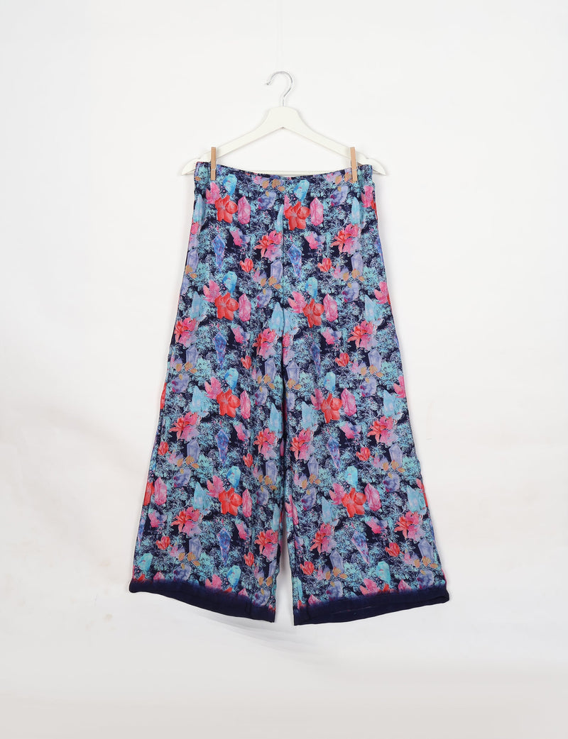 Blue floral patterned wide-leg pants hanging on white hanger against white background