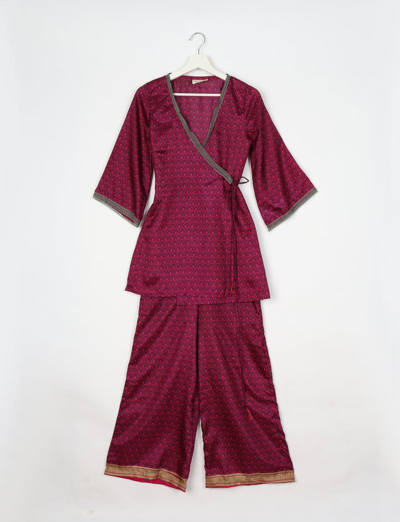Pink tunic set with micro dark pink pattern, wrap-style top with gray trim, and wide-leg pants with gold border, flat lay