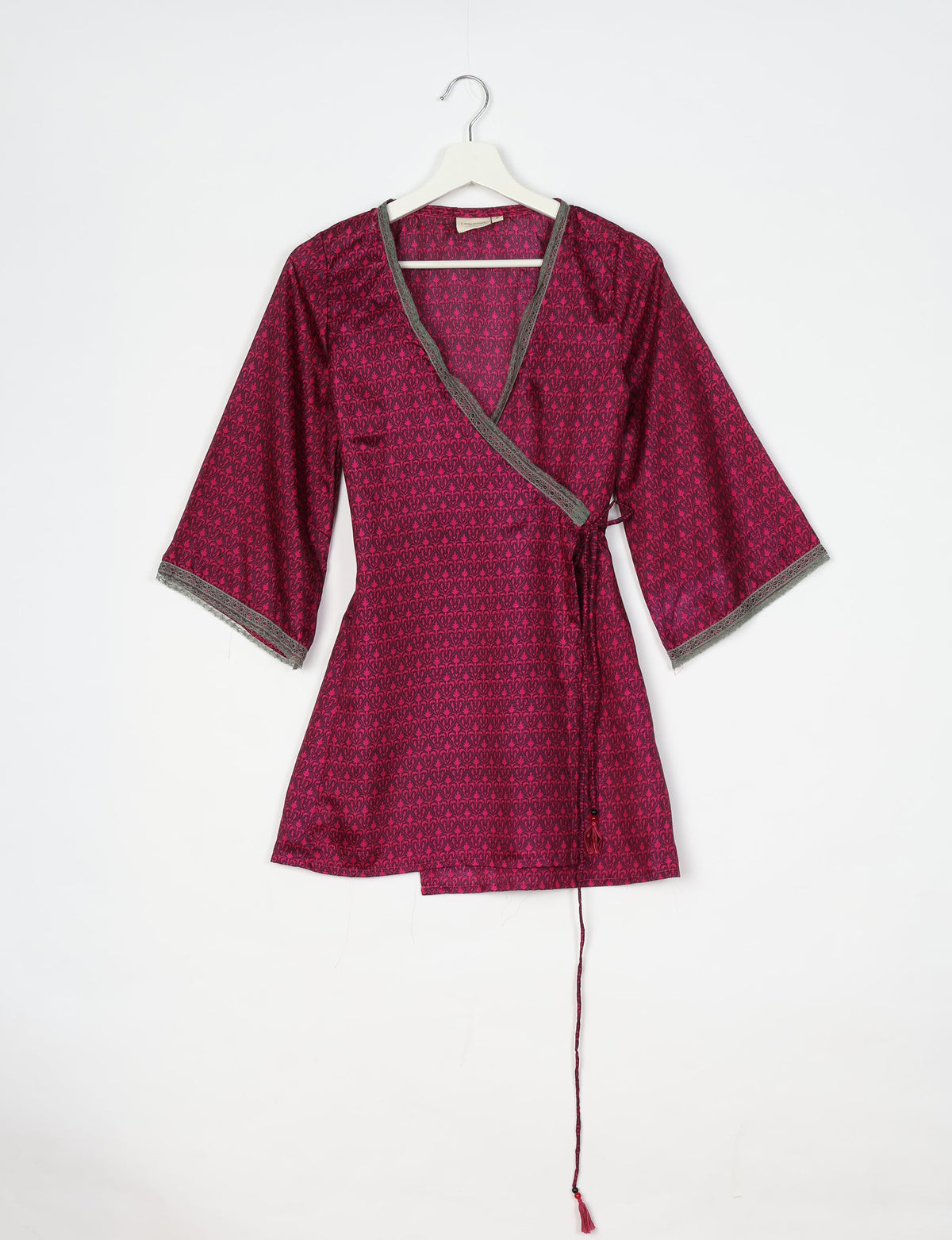 Pink tunic with micro dark pink pattern, V-neck, gray lace trim on neckline and sleeves, and side tie with tassel, hanging