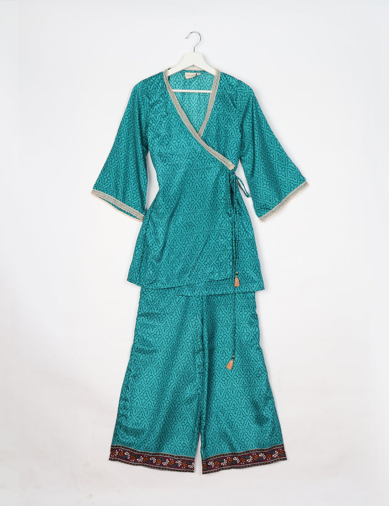 Blue abstract patterned tunic set with wrap top, lace trim, and wide-leg pants with floral border, hanging on white hanger