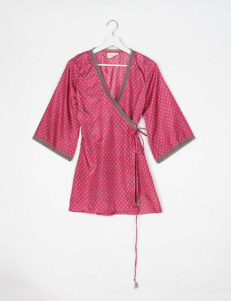 Pink wrap tunic with small gray floral print, gray lace trim on neckline and sleeves, hanging on white hanger front view