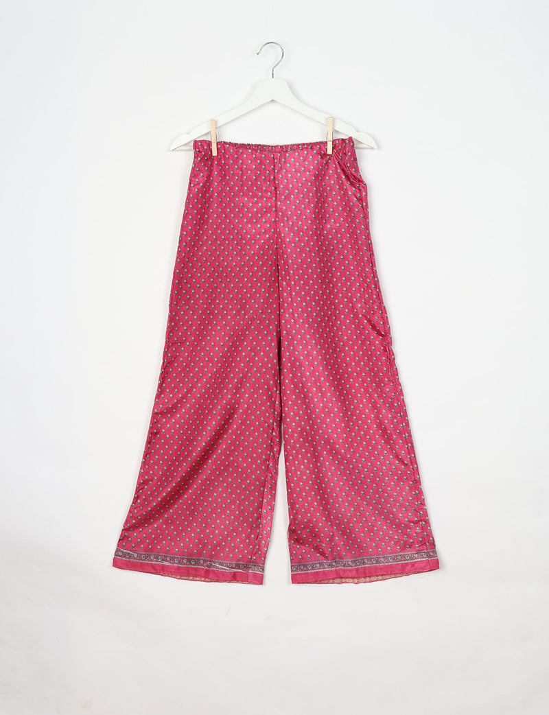 Pink tunic set pants with micro floral design and decorative border at hem, hanging on white hanger against white background
