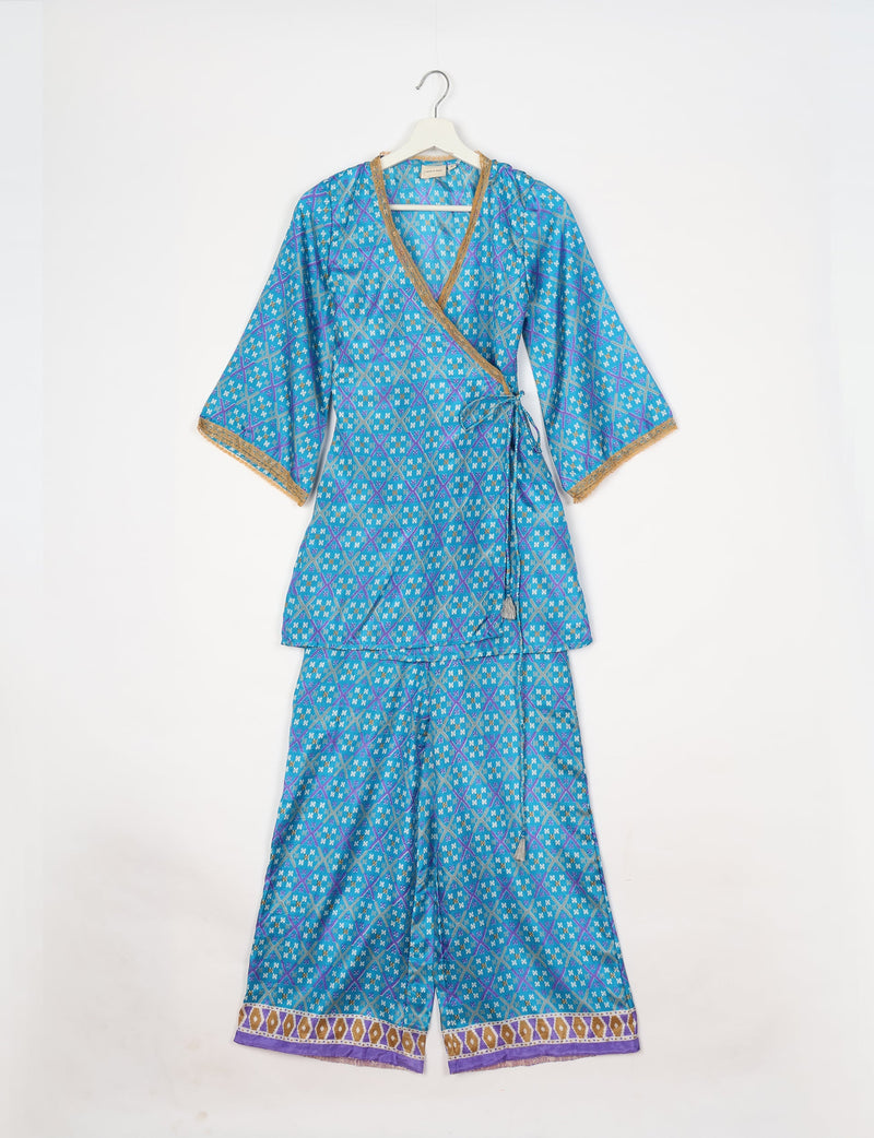 Blue geometric patterned tunic set with wrap top, gold trim on neckline and sleeves, and matching wide-leg pants with border hem