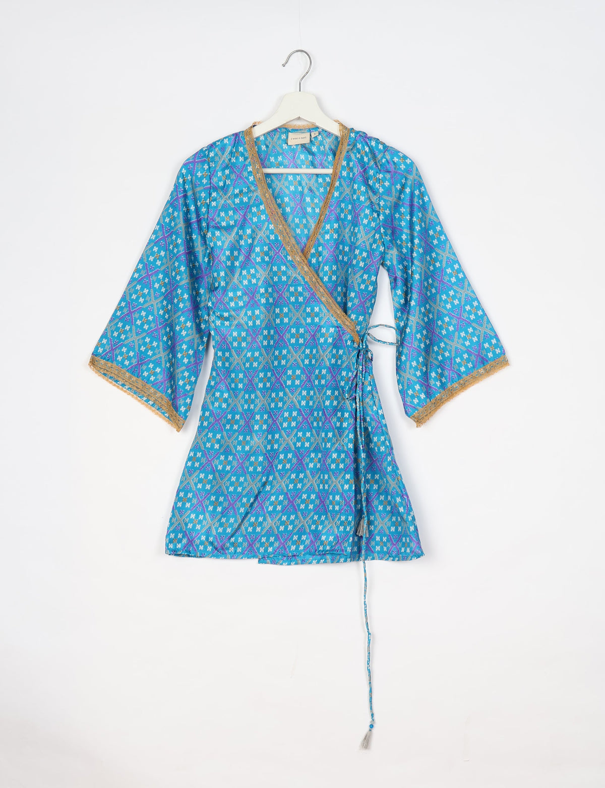Blue geometric patterned wrap tunic with gold trim on neckline and sleeves, hanging on white hanger against white background