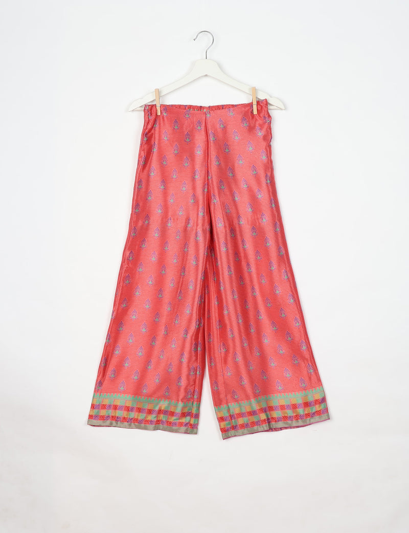 Pink wide-leg pants with purple micro design and multicolor checkered border, hanging on white hanger with clips