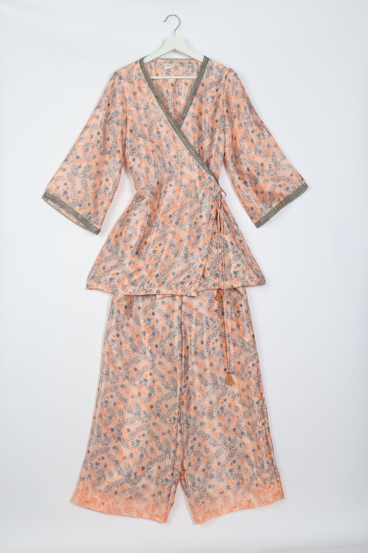 Pink floral print tunic set with wrap front, three-quarter sleeves, green lace trim, and matching wide-leg pants on hanger