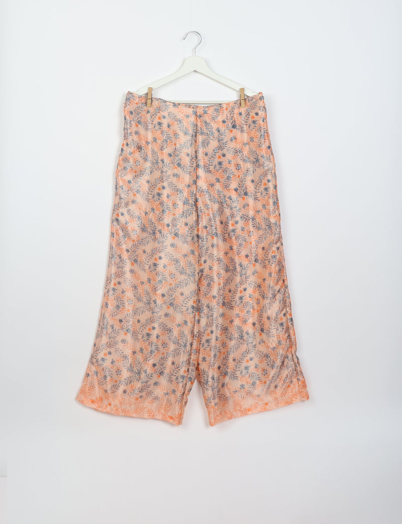 Pink and gray floral patterned wide-leg pants hanging on a white hanger against a white background