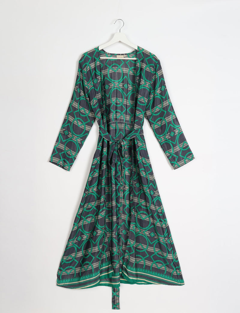 Green and black geometric patterned beach robe with long sleeves and a waist tie, hanging on a white hanger