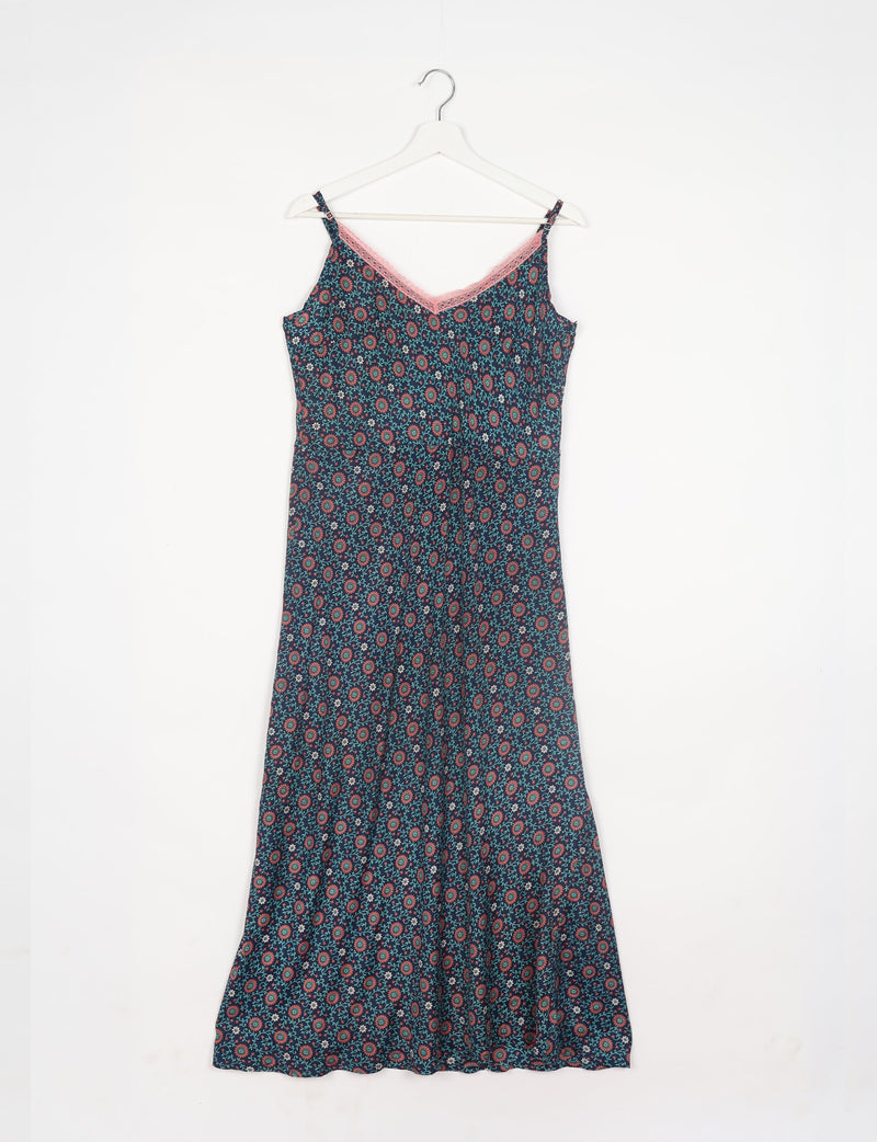 Blue tropical strap dress with adjustable straps and pink lace trim on neckline, hanging on white hanger, front view