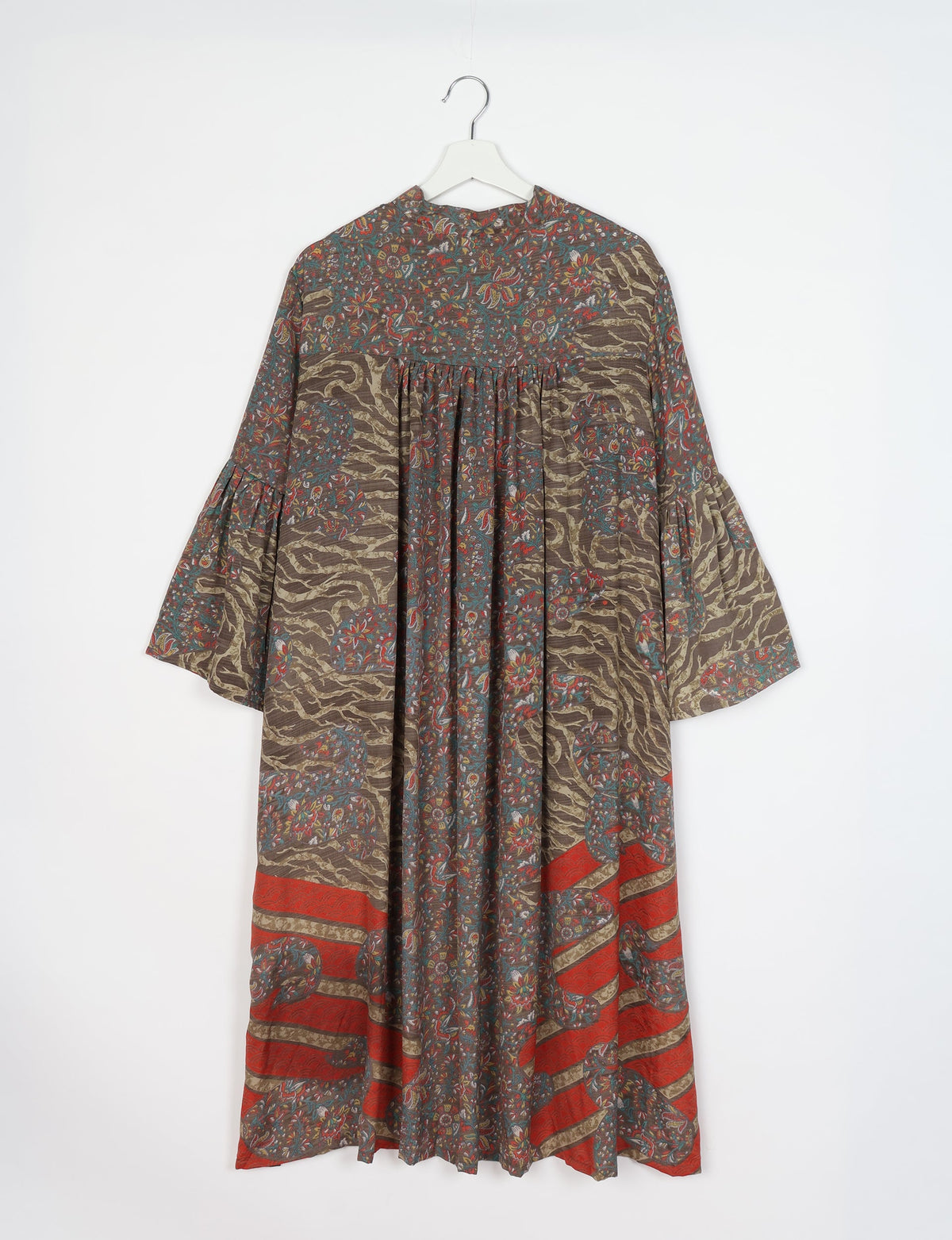 Brown tropical patterned bell sleeve coat with floral and abstract designs, hanging on white hanger, front view