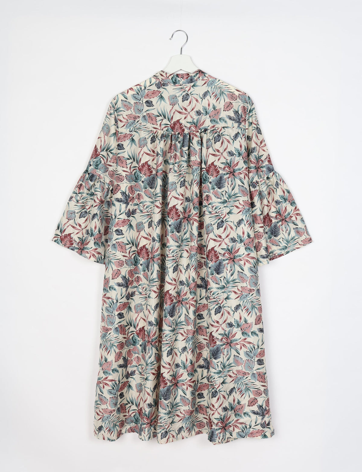 White bell sleeve coat with red, blue, and gray leaf print, shown from back on white hanger against white background