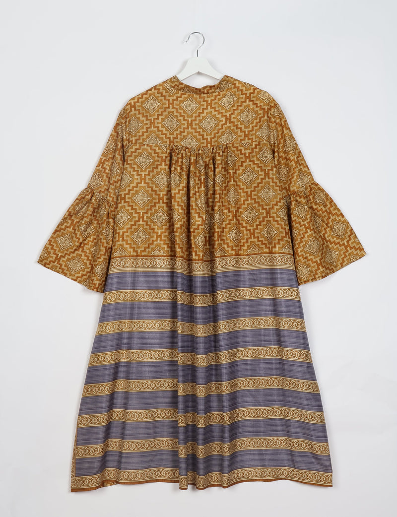 Yellow geometric patterned bell sleeve coat with gathered back and horizontal striped border, shown hanging on white hanger