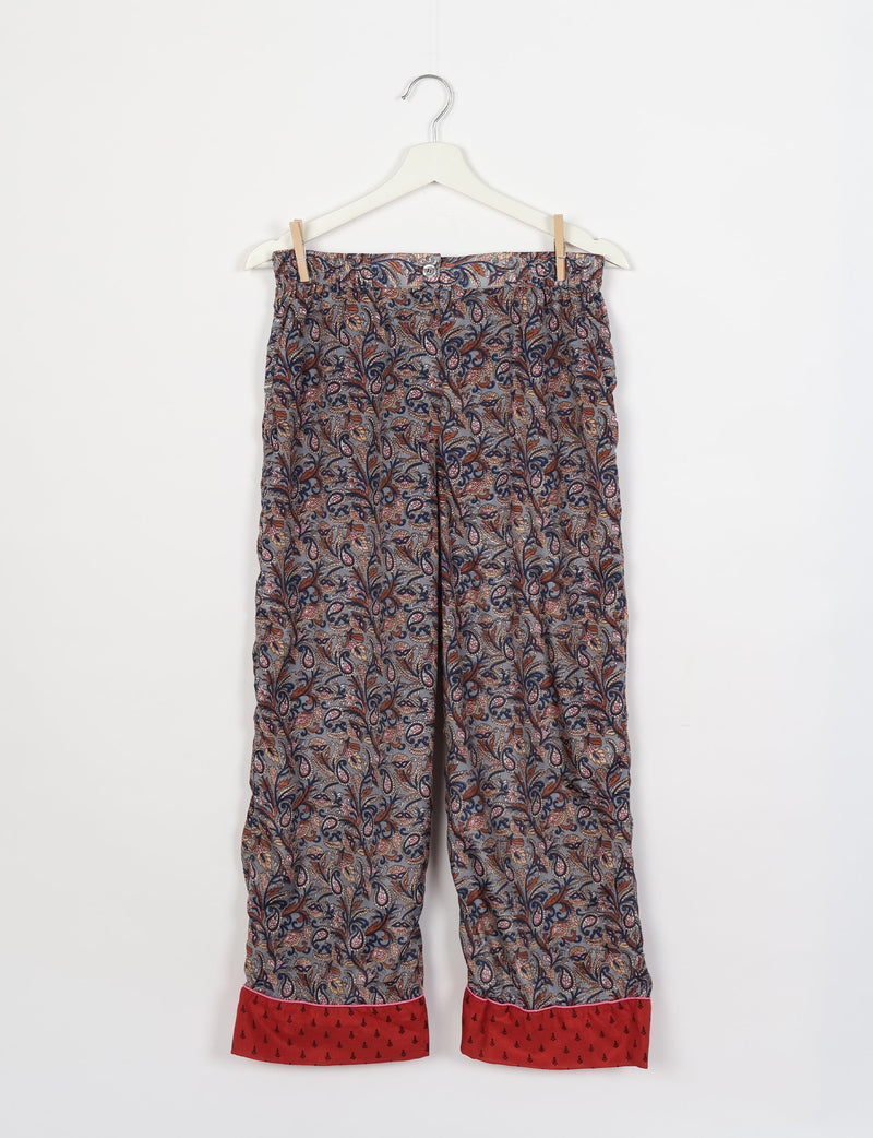 Grey tropical patterned pajama pants with red cuffs and button closure hanging on white hanger against white background
