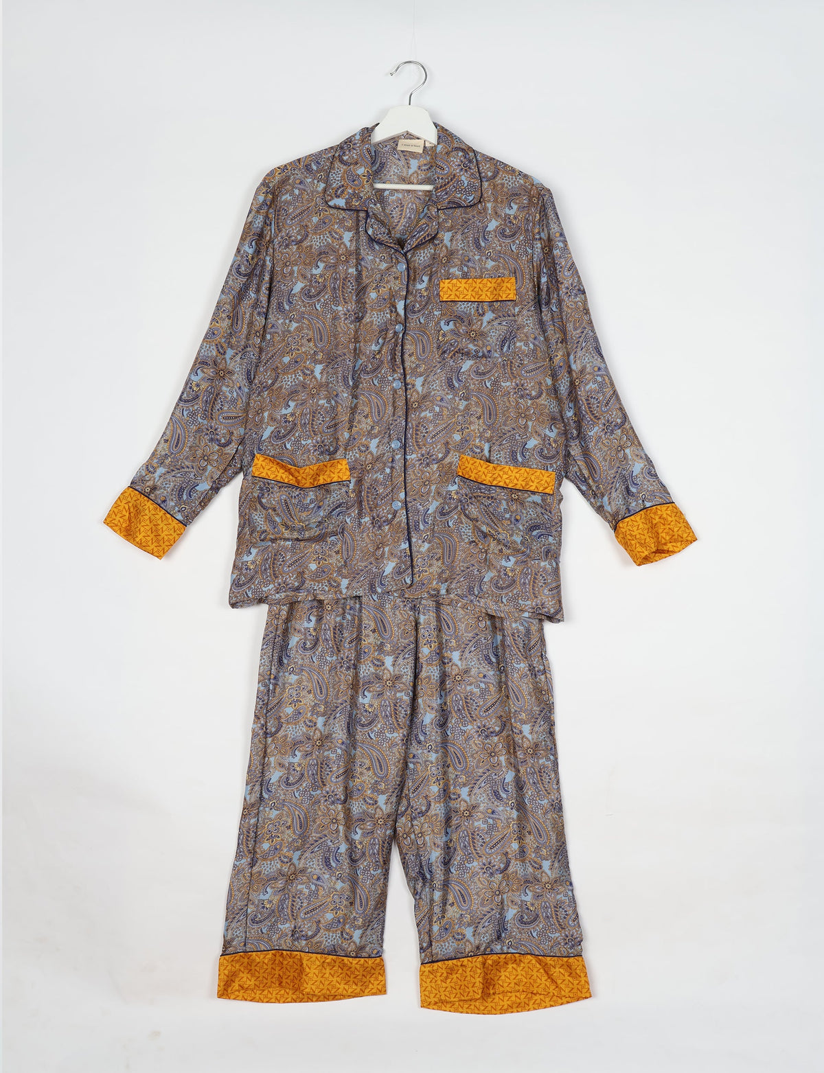 Long-sleeve pajama set with blue and brown paisley pattern, yellow cuffs, pocket trims, and button-front shirt on hanger