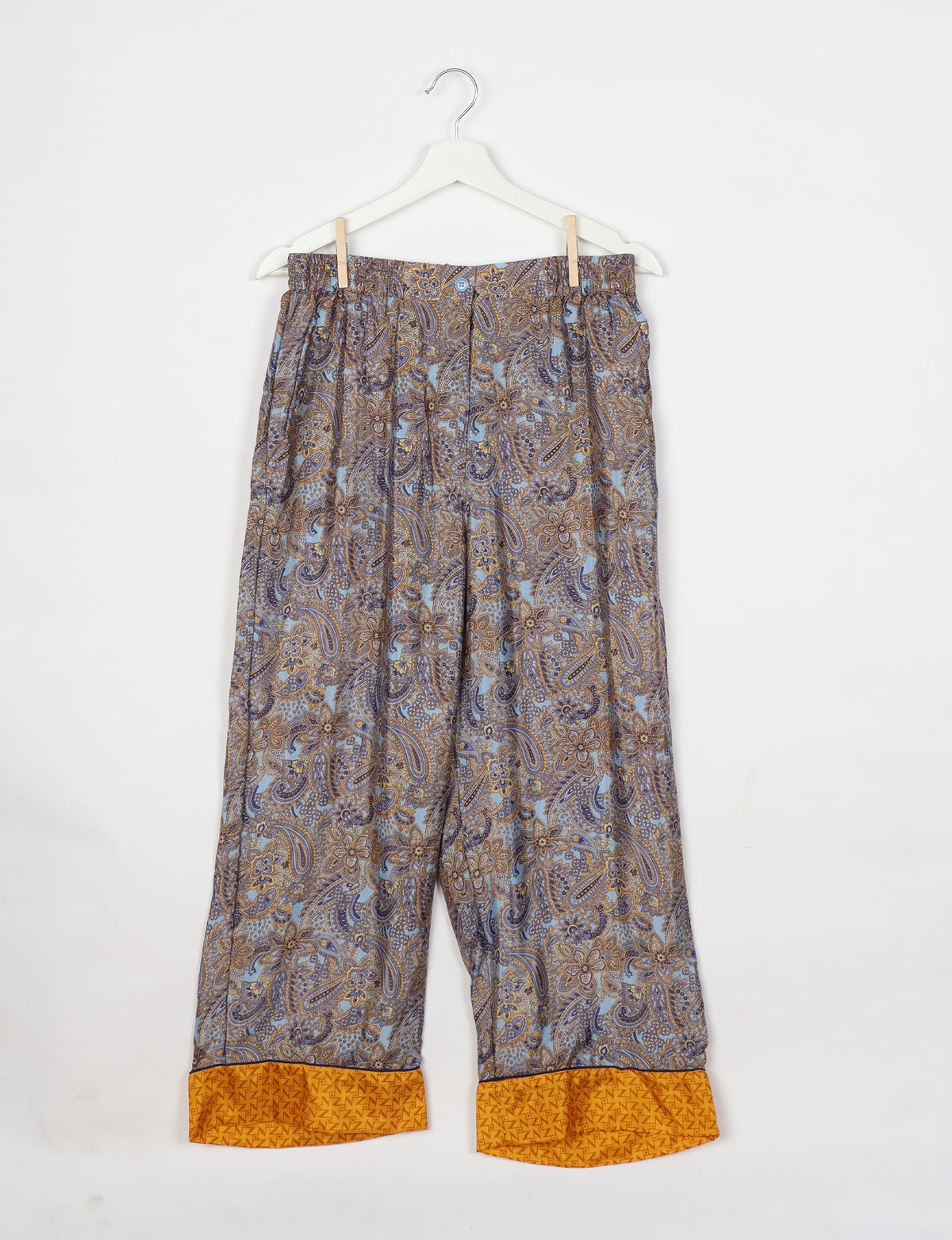 Paisley patterned pajama pants with elastic waistband and yellow cuff detail, hanging on white hanger against white background