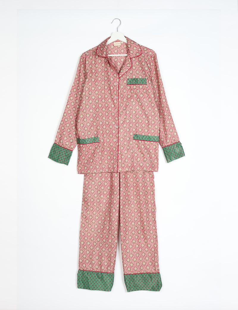Long-sleeve pajama set in pink with a small floral pattern and contrasting green cuffs and pocket trim, hanging on a white hanger