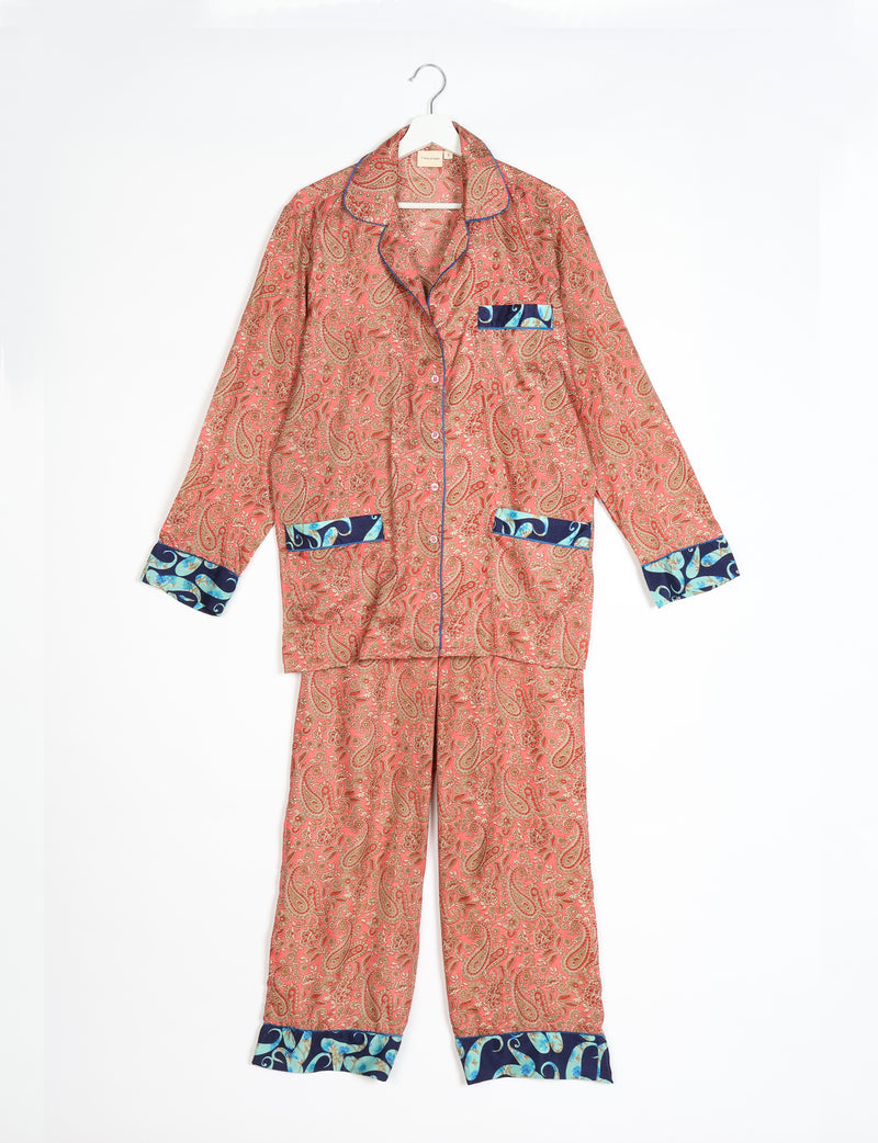 Orange paisley long-sleeve pajama set with blue floral trim on cuffs, pockets, and collar, hanging flat on white background
