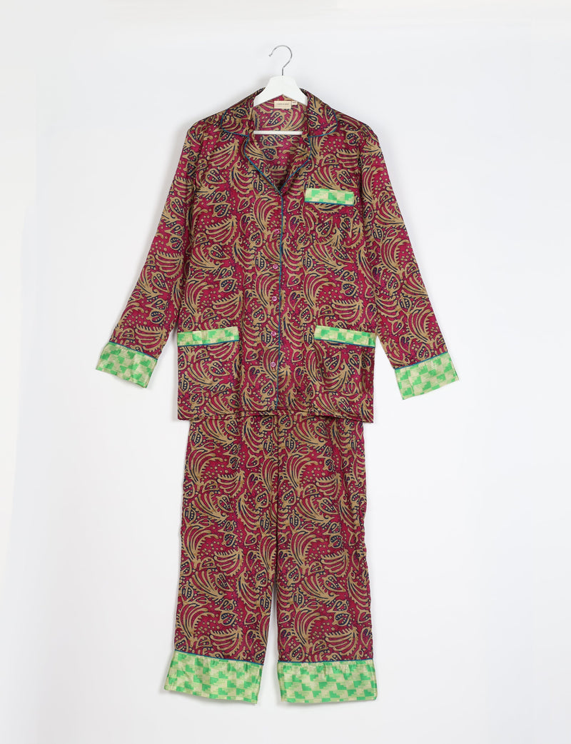 Long-sleeve red abstract print pajama set with green checkered cuffs and pocket trim, hanging on white hanger