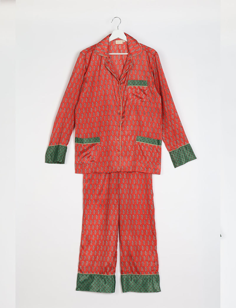 Orange long-sleeve pajama set with micro floral print, green patterned cuffs and pockets, hanging on white hanger front view