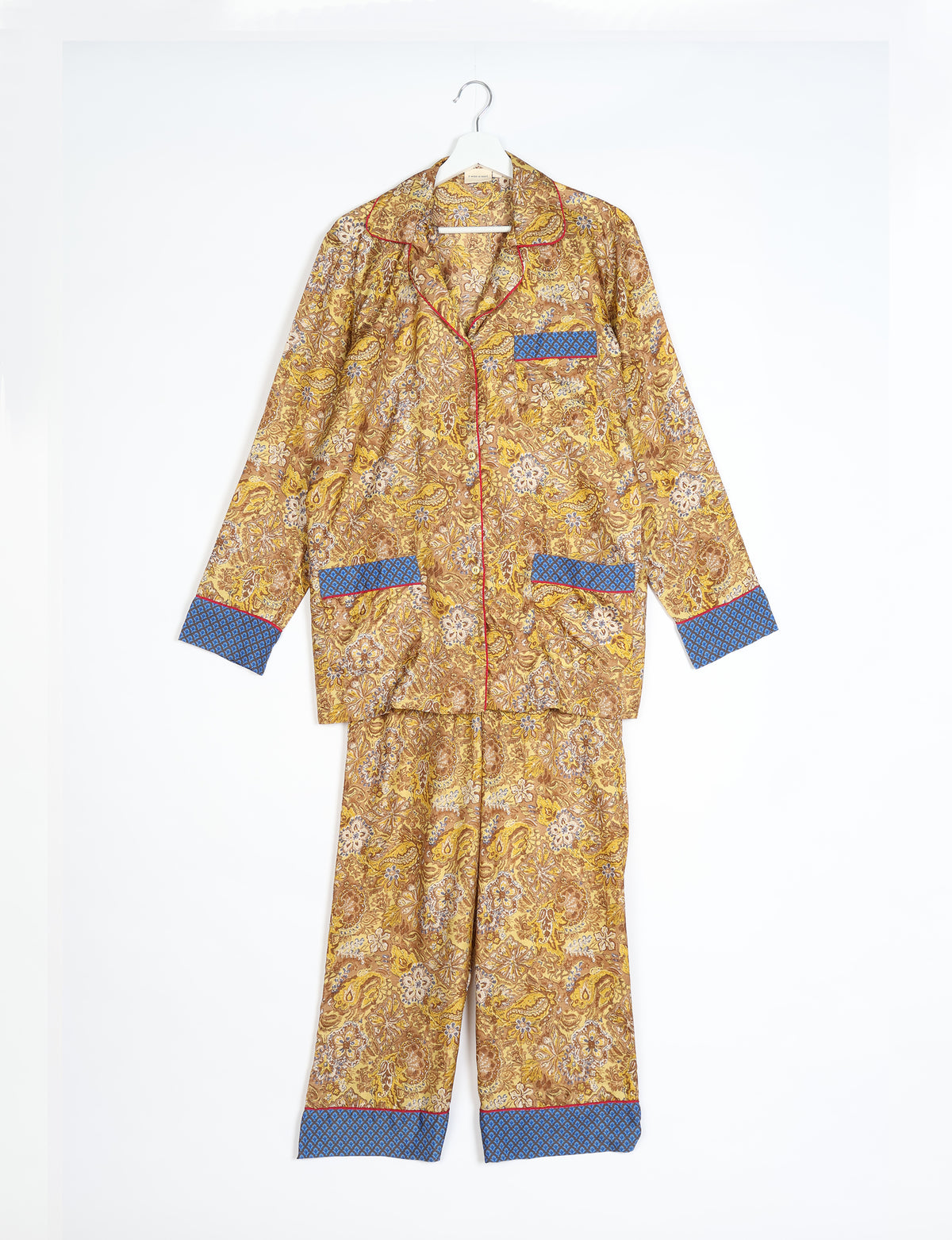 Yellow tropical long-sleeve pajama set with blue patterned cuffs and pockets, hanging flat on a white background