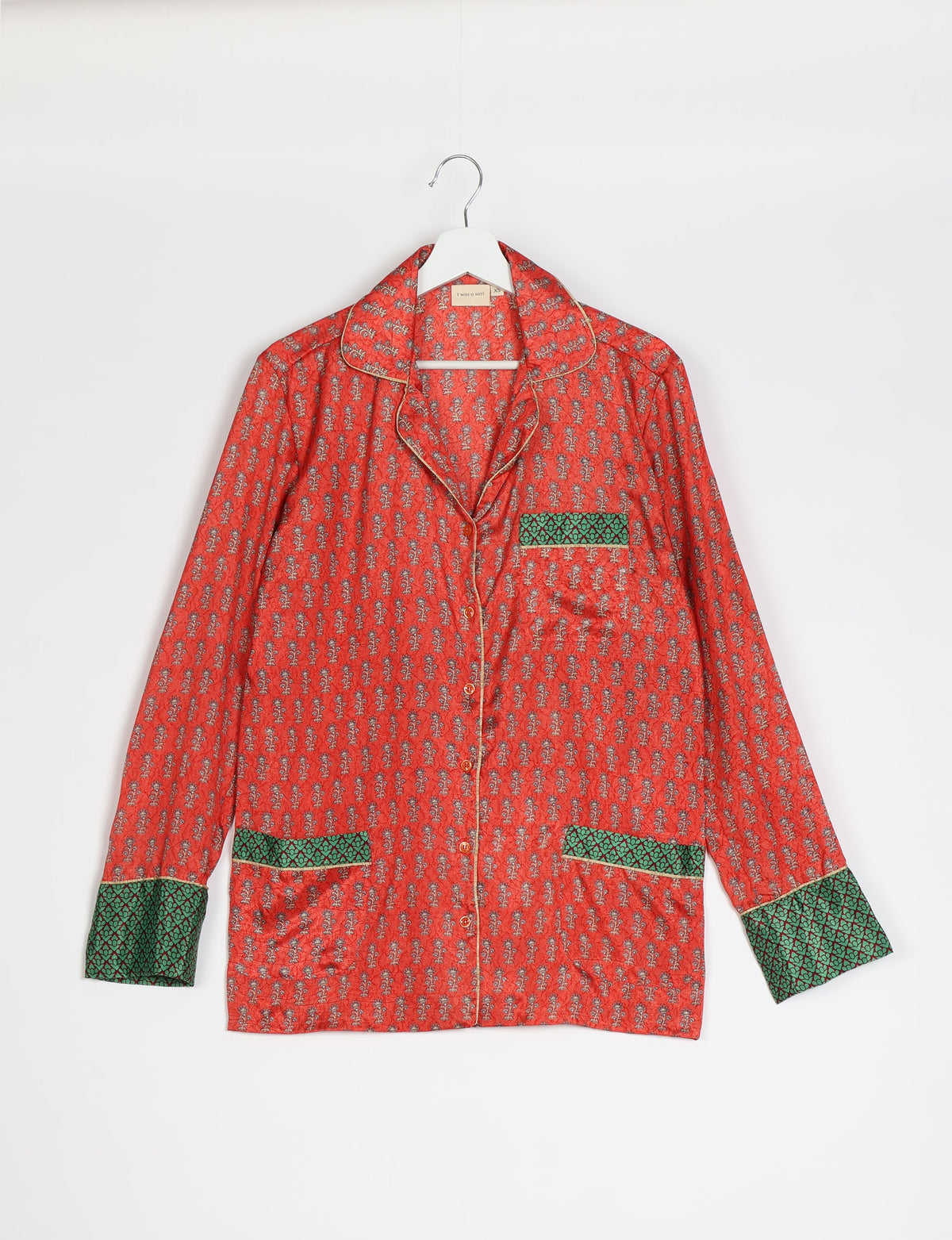 Orange long-sleeve pajama top with micro floral print, green patterned cuffs and pockets, button front, on white hanger