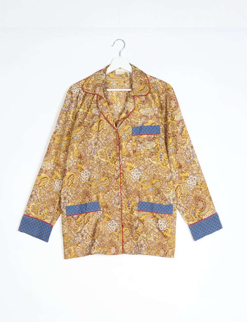 Yellow tropical print long-sleeve pajama top with blue patterned cuffs and pockets, red piping, hanging on white hanger