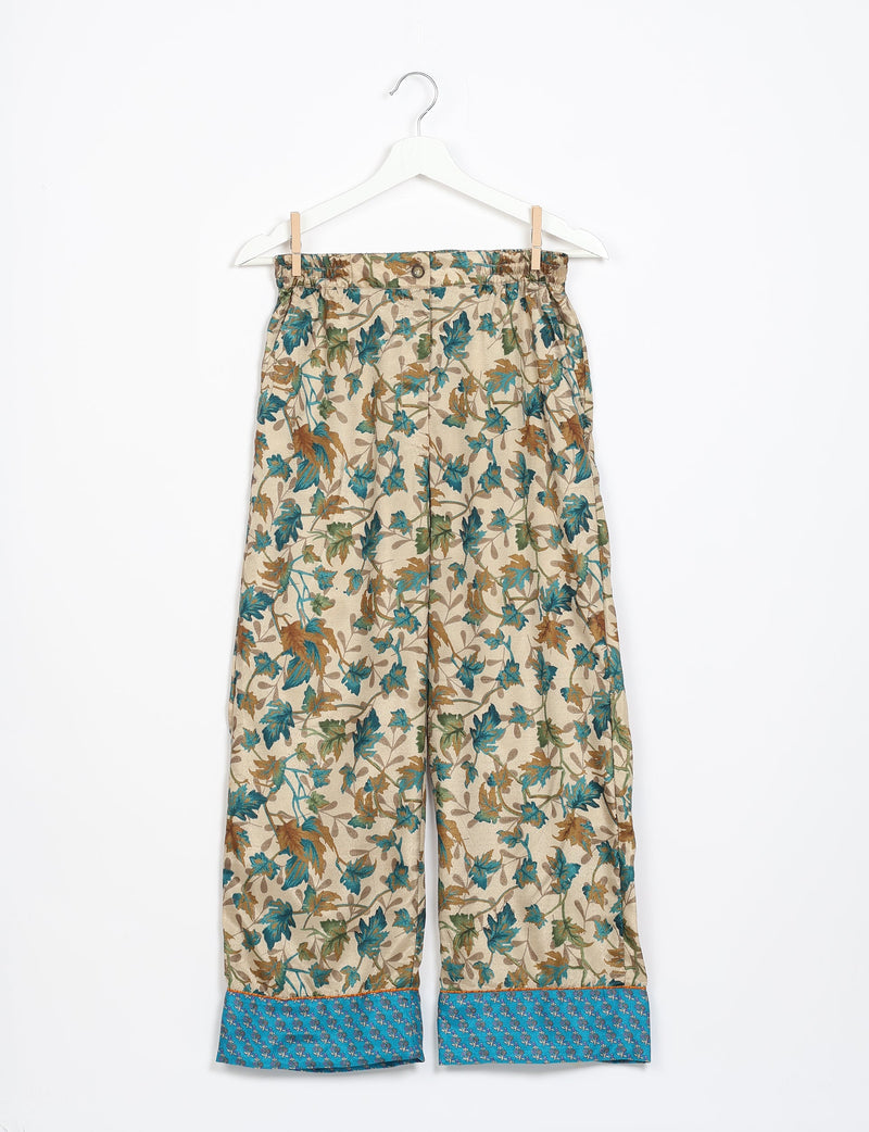 Beige pajama pants with long sleeves, featuring a blue and brown leaf pattern and blue cuffs with small floral print